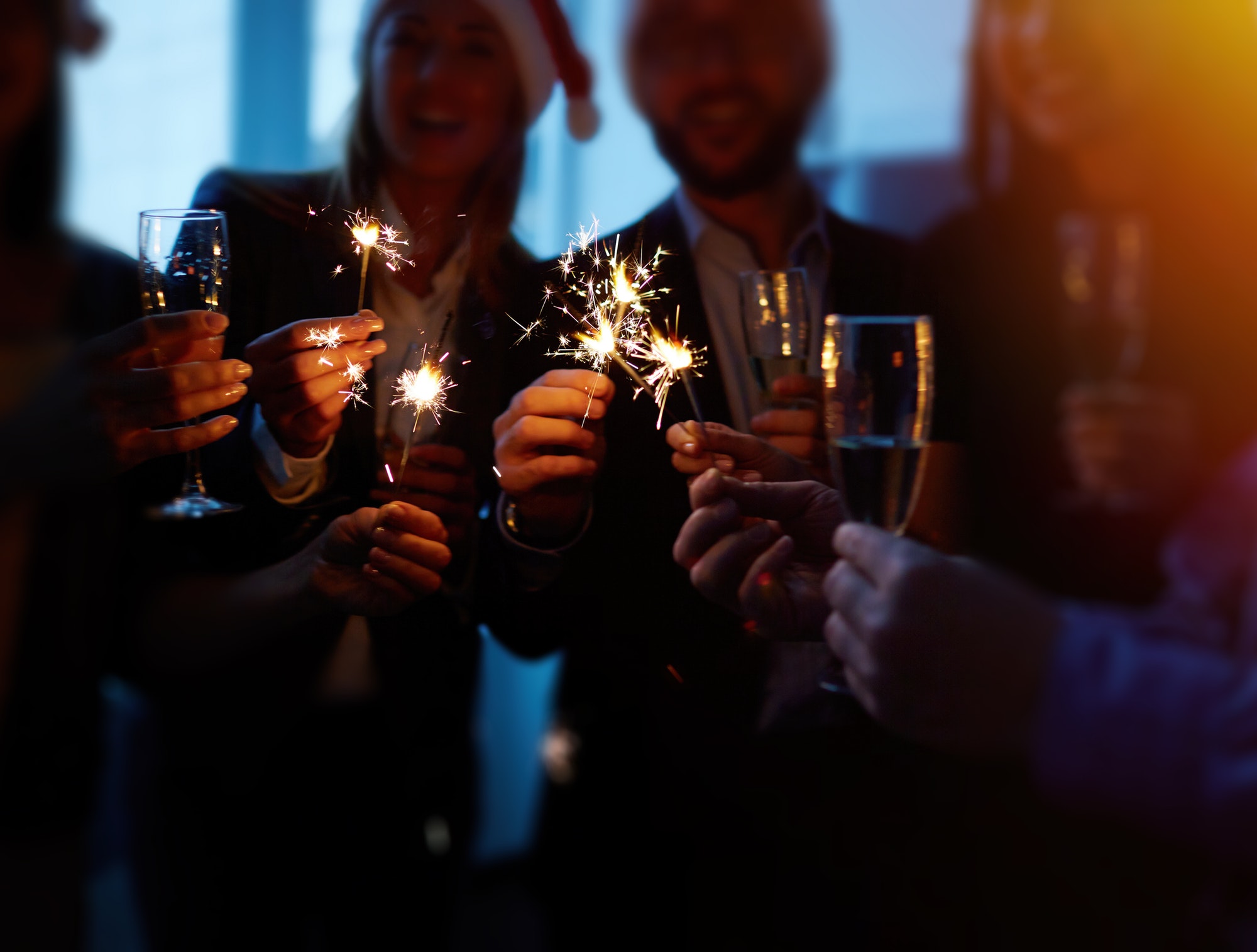 Group of people celebrating with sparklers and champagne glasses.