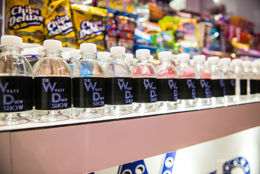 Row of branded bottled beverages on display with assorted snacks in the background.