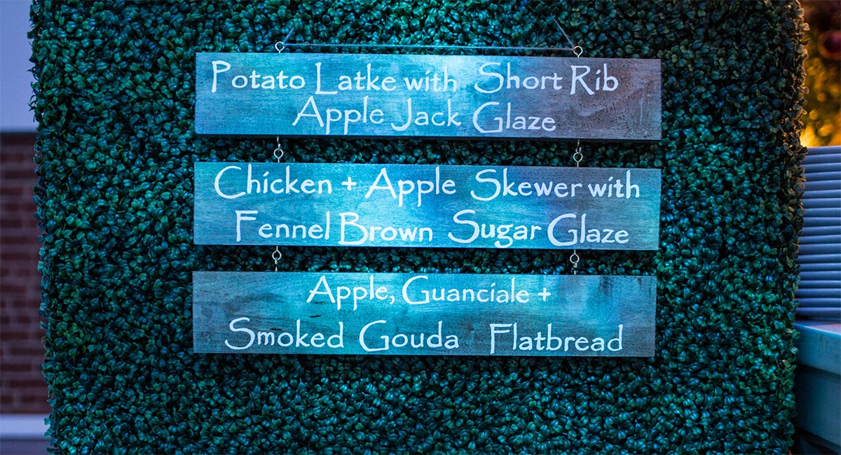 Three-tiered menu sign featuring seasonal dishes with apple-themed ingredients.