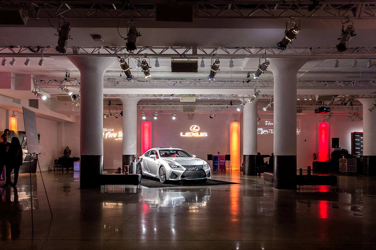 A lexus car on display at an indoor event with dramatic lighting and banners.